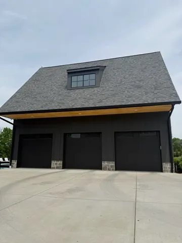 Black solid garage doors with no windows on a dark-sided garage