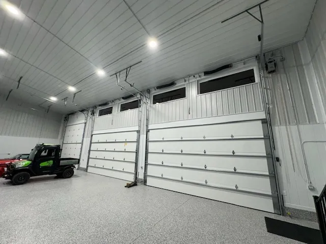 Inside a white shop: three high-lift doors with their tracks and springs run up the wall