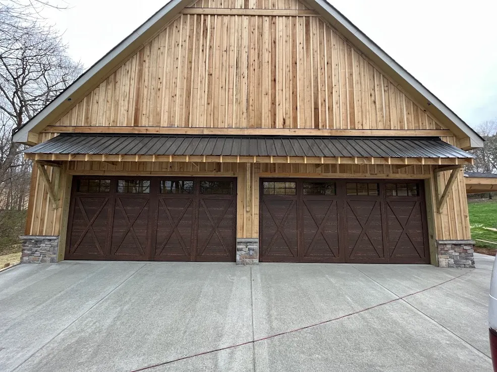 Two stained walnut carriage doors with X-brace panels under a cedar-clad gable